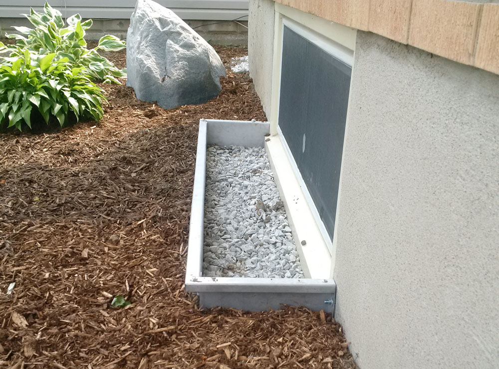 Modern Square Stainless Steel Egress Window Well with FauxRock in background