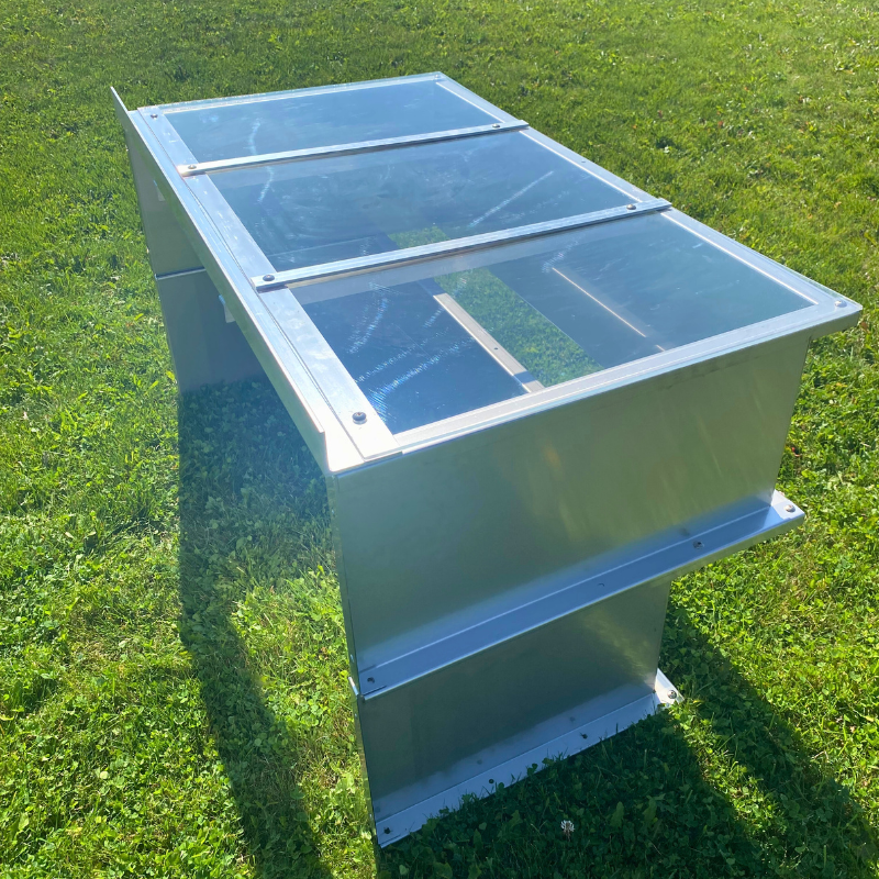 A photo of a tiered window well with a a window well cover on it taken outside in the grass