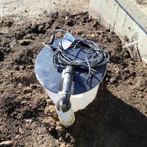 a photo of an outdoor sump pump in dirt