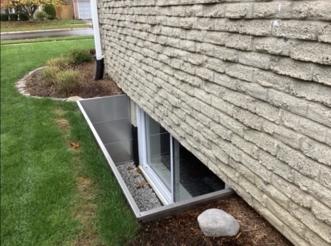 A photo of a gravel filled Modern Square Window Well on the outside of a home.